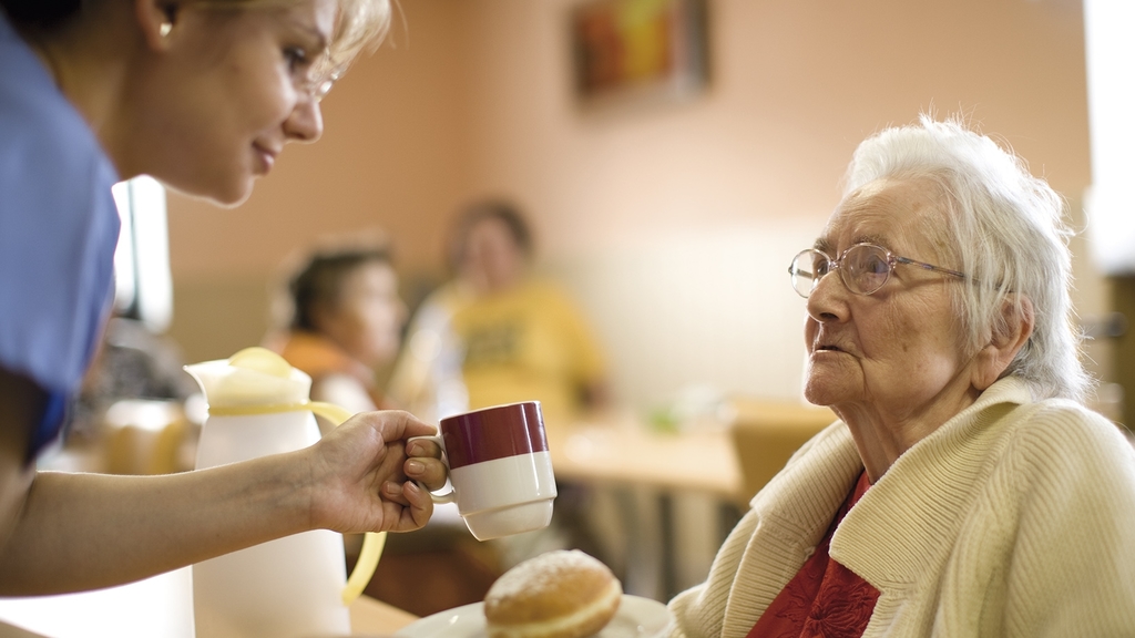 Vergrößerung des Bildes für Pflegerin mit Seniorin im Pflegeheim beim Essen.