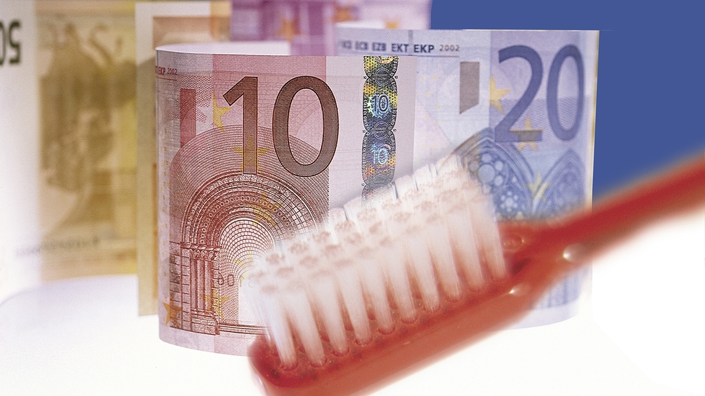 Vergrößerung des Bildes für Zahnbürste mit Geldscheinen im Hintergrund.