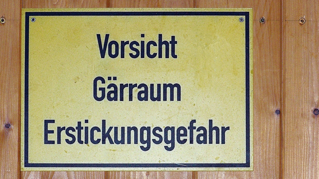 Vergrößerung des Bildes für Das gelbe Schild mit schwarzem Rand hat die Aufschrift "Vorsciht - Gärraum - Erstickugnsgefahr" und hängt an einer Holztür..