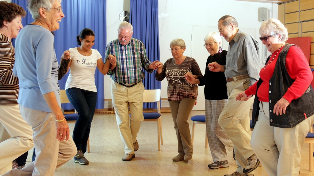Senioren und Übungsleiterin bei Bewegungsübungen in einem Trittsicher-Kurs