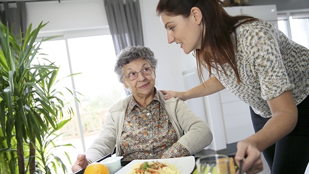 Pflegekraft mit Seniorin beim Essen