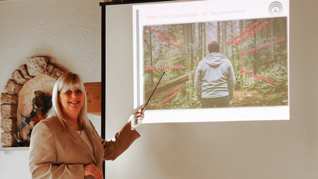 Vergrößerung des Bildes für Präventionsfachfrau Petra Müller steht vor Leinwand und zeigt mit einem Stab darauf..