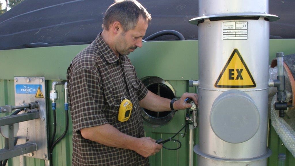 Vergrößerung des Bildes für Bild: Mann überprüft Gerät einer Biogasanlage.