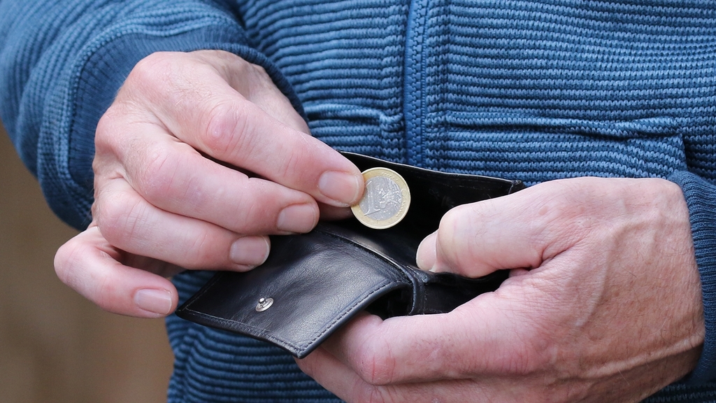 Detailfoto zeigt Männerhände, die einen Euro aus einem Portemonaie nehmen
