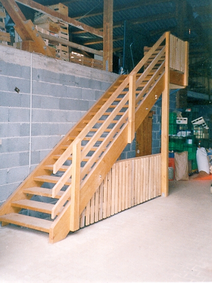 Eine neue Holztreppe führt zur zweiten Etage einer landwirtschaftlichen Lagerhalle