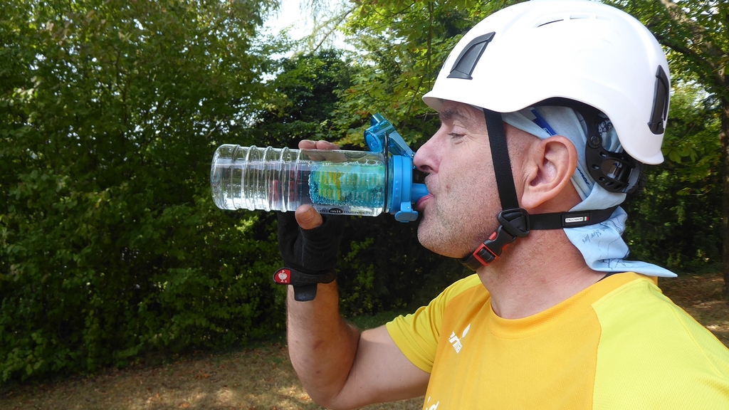 Vergrößerung des Bildes für Ein Mann mit Helm trinkt eine Flasche Wasser.