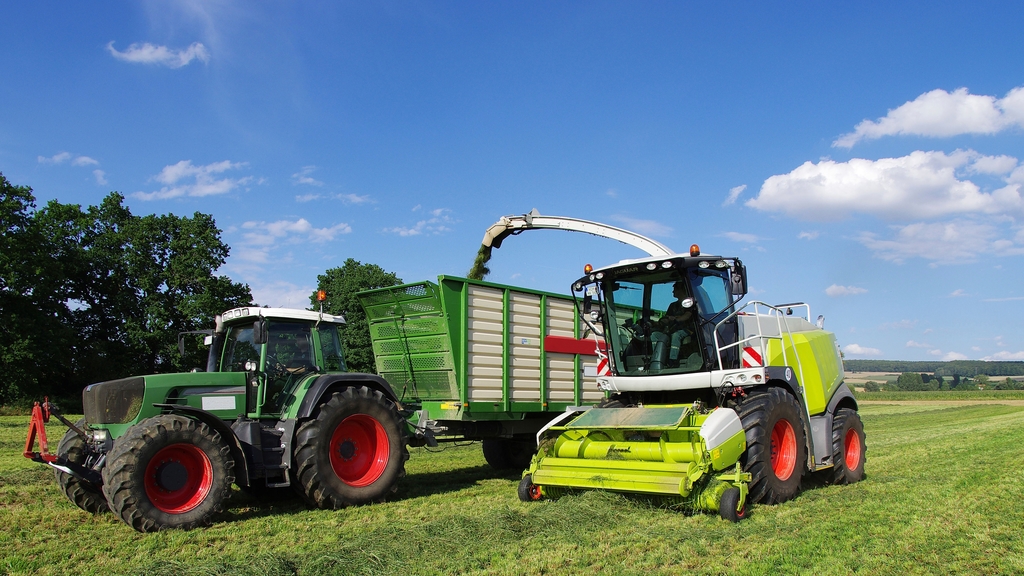 Vergrößerung des Bildes für Feldhäcksler auf dem Feld befüllt Traktor.